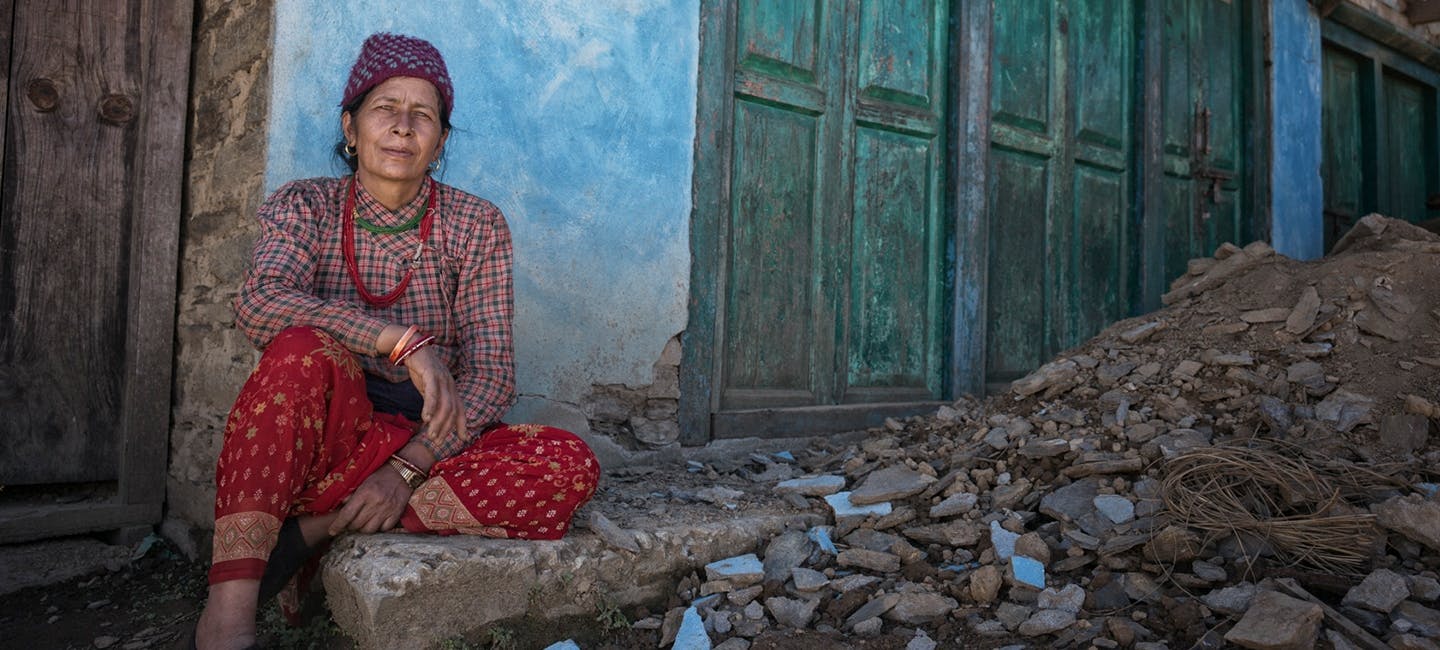 Nepalese woman sitting in front of building and next to bricks