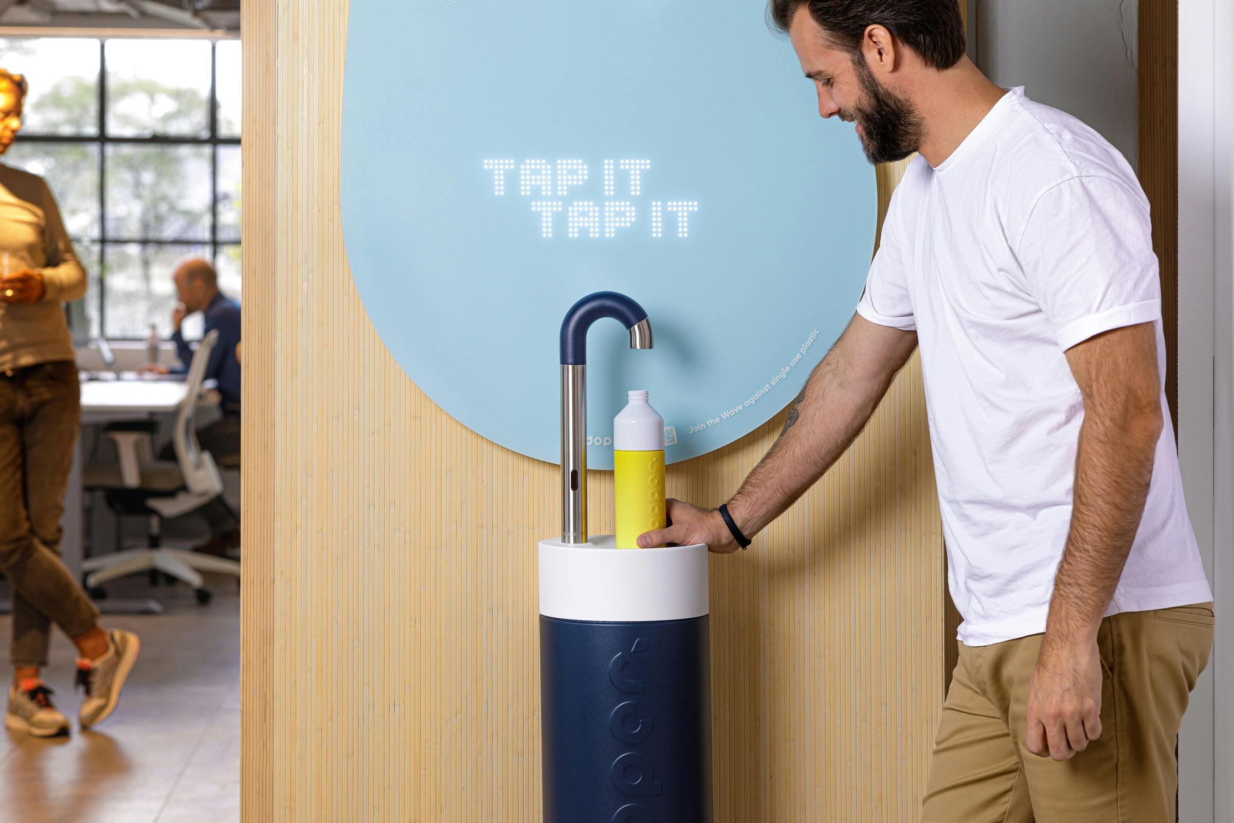 Person standing next to a blue Dopper Water Tap