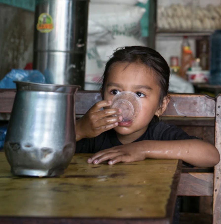 Nepalese girl drinking water from a cup
